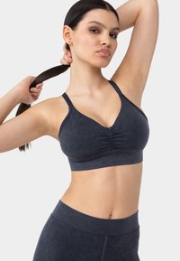 Bralette de tela suave en azul marino, con diseño de escote en V, fruncido en el centro y tirantes delgados. Combinado con una parte inferior alta a juego.