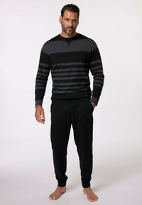 Chemise rayée noire et grise à manches longues avec un col rond, associée à un pantalon noir. Le tissu semble doux et confortable.