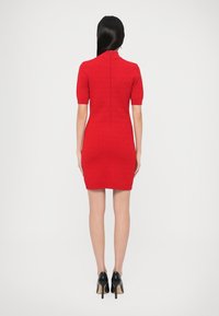 Rochie roșie mulată cu mâneci scurte, model texturat și fermoar la spate. Purtați cu pantofi negri cu toc înalt. Design simplu și elegant.