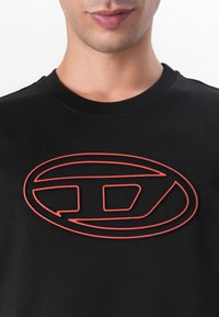 Svart bomull t-skjorte med et fremtredende rødt konturlogo-design. Rund hals og korte ermer med en glatt tekstur.