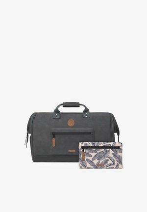 Trousse grise en toile avec une surface texturée, des accents en cuir et des poignées supérieures, accompagnée d'une pochette crème ornée d'un motif de feuilles foncées et d'une fermeture éclair.