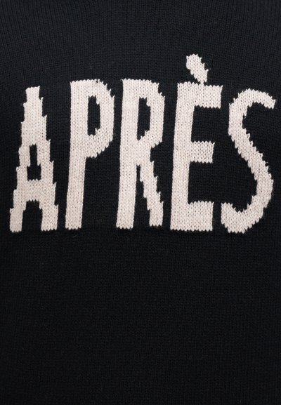 Fehér kötött betűk, amelyek „APRÈS”-t írnak egy fekete kötött anyag háttér előtt.