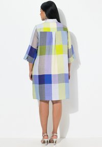 Abito a quadri colorati in tessuto leggero, con una combinazione di quadrati blu, verdi e grigi. Presenta un colletto e maniche a tre quarti.