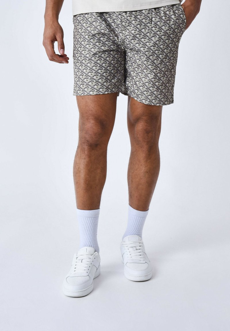 Pantalones cortos grises con un diseño geométrico, con cordón en la cintura, combinados con zapatillas blancas y calcetines.
