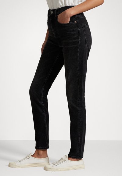 Hoge taille zwarte denim jeans met een slim fit, voorzien van vijf zakken en subtiele stiksels. G gedragen met ivoorkleurige sneakers.