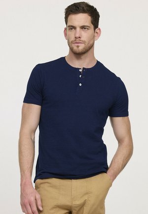 T-shirt henley à manches courtes bleu marine avec un col rond et une patte de boutonnage à trois boutons. Texture lisse avec un design ajusté et sans motifs.