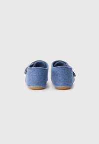 Chinelos de feltro azuis com uma forma arredondada, textura suave e sola de borracha bege. Apresentam uma tira lateral para fecho. Design simples e minimalista.