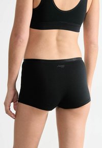 Schwarze nahtlose Boxershorts mit einer glatten Textur und einem weichen Bund. Das Produkt verfügt über ein dezentes Logo in der Nähe der hinteren Taille.