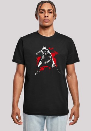 Schwarzes T-Shirt mit einem grafischen Druck eines maskierten Charakters in Graustufen, vor einem Hintergrund mit roten Spritzern. Kurze Ärmel, Rundhalsausschnitt.