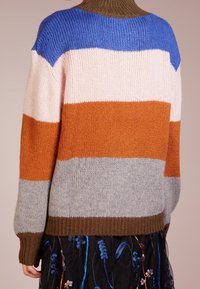 Flerfärgad stickad tröja med horisontella ränder i blått, rosa, orange och grått, med ribbad krage och ärmslut.