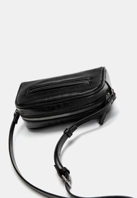 Svart läder crossbody-väska med dragkedjestängning, rektangulär form, slät yta och justerbar rem.