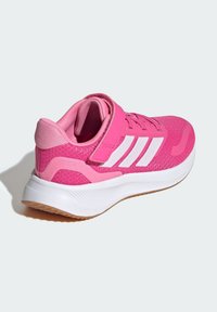 Shoe de sport rose avec une tige en mesh, une sangle Velcro, des accents blancs et une semelle intermédiaire blanche. Présente une semelle extérieure texturée pour une meilleure adhérence.