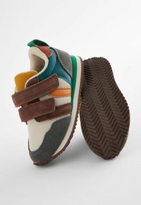 Wielokolorowe dziecięce sneakersy z siateczką i zamszowym wierzchem, z zielonymi, brązowymi, pomarańczowymi i żółtymi akcentami oraz teksturowaną gumową podeszwą.