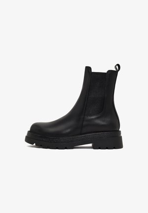 Zwarte leren Chelsea boot met elastische zijpanelen, ronde neus en getextureerde rubberen zool. Voorzien van een lus aan de achterkant.