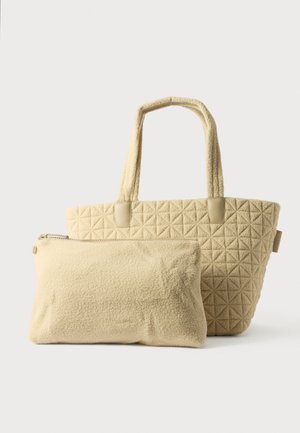 Sac fourre-tout beige avec un motif de triangle matelassé, doté de deux poignées et d'une pochette assortie amovible avec une fermeture éclair. Texture douce.