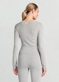 Grauer, gerippter Langarmpullover mit rundem Ausschnitt und figurbetonter Silhouette. Auffälliges Etikett auf der Rückseite, gefertigt aus weichem Strickmaterial.