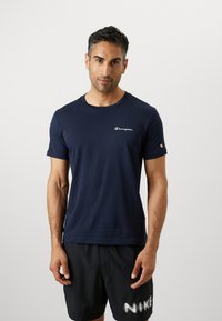 Donkerblauwe T-shirt met korte mouwen van katoen, met een klein wit 'Champion' logo op de borst en een ronde halslijn.