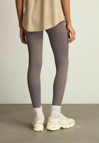 Grå ribbede leggings med matchende ankelstrømper, parret med lyse sneakers. Toppen har en løs, lys beige tekstur.