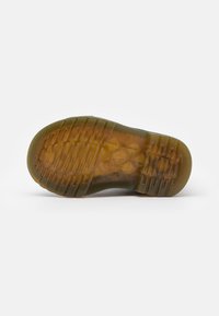 Semelle de chaussure en caoutchouc olive vert avec des motifs de grip texturés, présentant une couche transparente et un emblème intégré au centre.