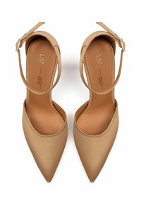 Dei tacchi beige a punta con finitura satinata, dotati di una sottile cinghia per la caviglia e di una soletta morbida e testurizzata. Design elegante e slanciato.