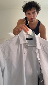 White and navy striped shirt on a hanger, featuring a button-down collar and a tag with "Massimo Dutti" logo. Smooth fabric texture.