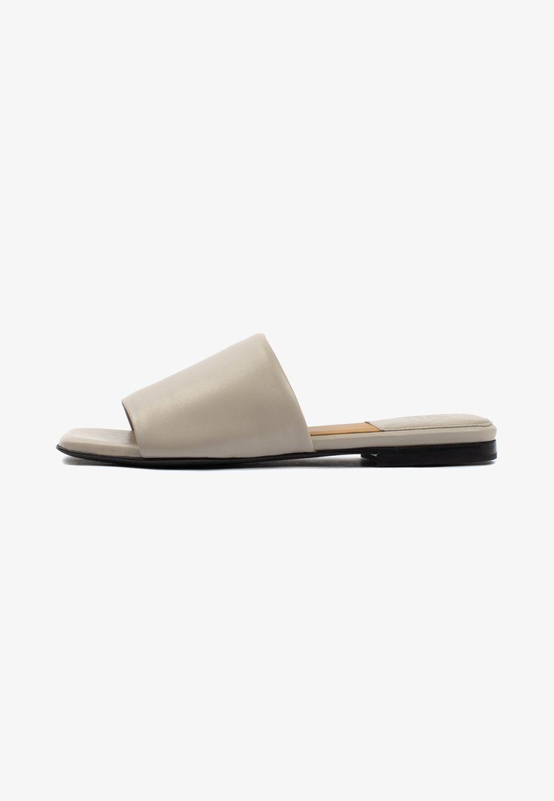 Sandali slide in pelle beige con punta aperta, caratterizzati da una ampia fascia sulla parte superiore del piede e una suola piatta nera.