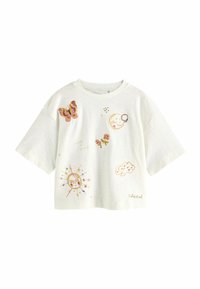 Camiseta blanca de manga corta con motivos celestiales bordados, que incluyen una mariposa, un sol, una luna y nubes en colores pastel y detalles en dorado.