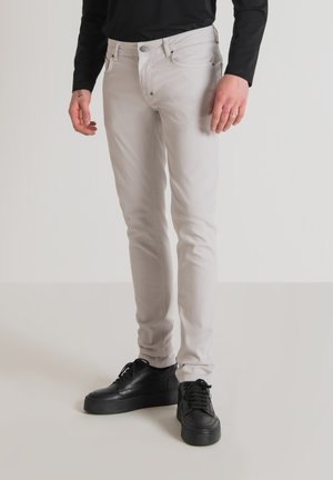 Vaqueros gris claro de denim, con un ajuste slim, diseño de cinco bolsillos y cierre de botón, combinados con zapatillas negras.