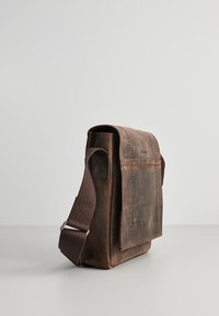 Borsa a tracolla in pelle marrone con finitura texture, tracolla in tessuto regolabile e tasca con pattina frontale. Design robusto con cuciture rinforzate.