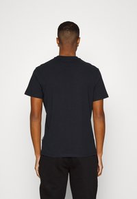 Mustat puuvillapaidat, pyöreä kaula-aukko, lyhyet hihat, tasapintainen malli ilman näkyviä kuvioita, muotoiltu leikkaus ja hieman sivusauman yksityiskohta.