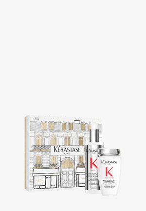 Coffret de soins capillaires Kérastase Paris comprenant une bouteille à pompe argentée et un pot blanc, présenté dans une boîte décorative avec des accents dorés et des illustrations.