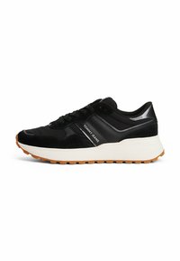 Zapatillas deportivas negras con materiales de ante y sintéticos, que presentan una entresuela blanca, suela de goma y el logotipo "TOMMY JEANS".