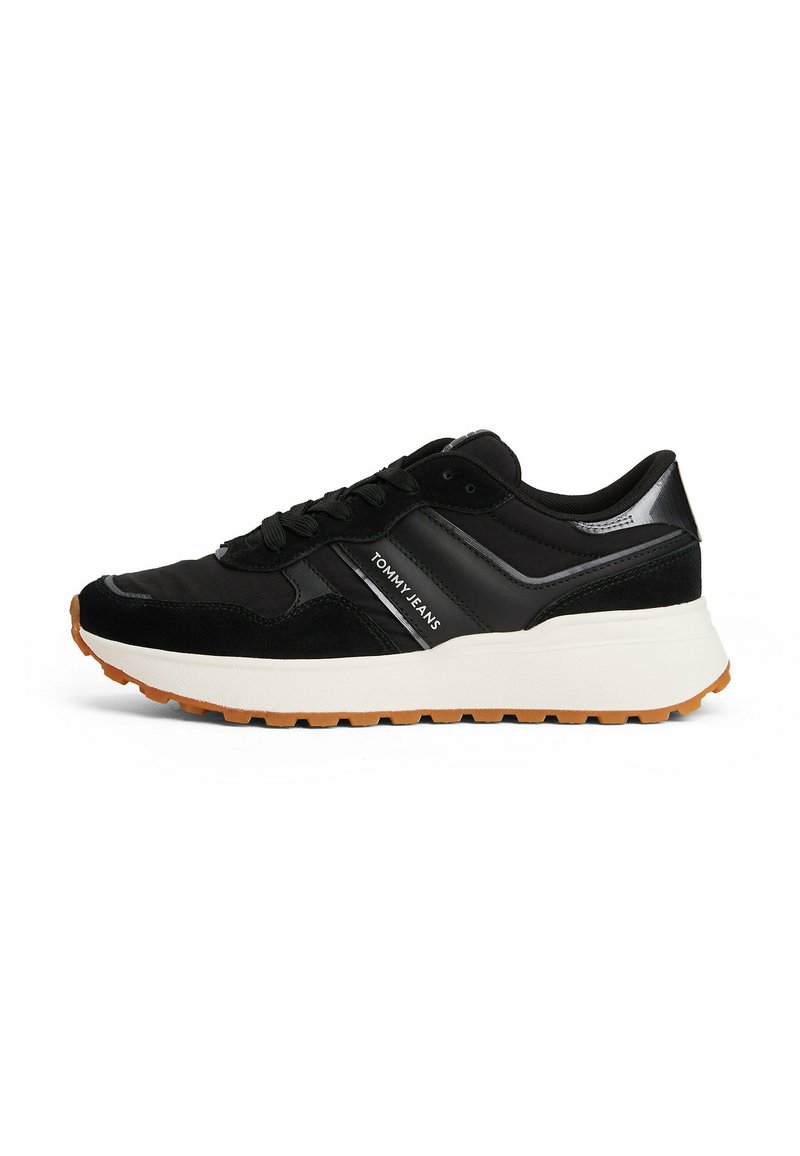 Zapatillas deportivas negras con materiales de ante y sintéticos, que presentan una entresuela blanca, suela de goma y el logotipo "TOMMY JEANS".