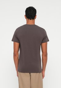 Brązowa koszulka z krótkim rękawem, wykonana z miękkiej bawełny, z okrągłym dekoltem i luźnym krojem, pokazana od tyłu, bez widocznych grafik.