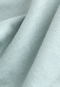 Tissu bleu clair texturé avec un motif côtelé subtil, affichant des fibres douces et une apparence drapée.