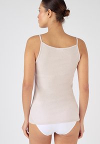 Top de tirantes finos en color beige claro, con textura suave y diseño ajustado. La vista trasera muestra un escote redondeado y líneas simples y limpias.