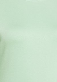 Mintgrön figurnära topp i mjuk, elastisk tyg. Har en rund halsringning och en enkel, sömlös design.