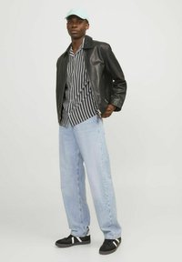 Sort læderjakke over en stribet skjorte, lyseblå denim jeans og sorte sneakers med hvide striber. Lyseblå kasket.