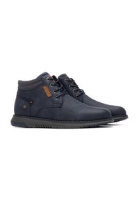 Botas de cuero azul oscuro con acentos grises, punta redonda, suela de goma antideslizante y detalles en marrón en los costados y los cordones. Diseño de caña alta.
