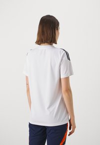 Witte sport T-shirt met korte mouwen, ronde halslijn en zwarte strepen op de schouders, gemaakt van een soepele, lichte stof.