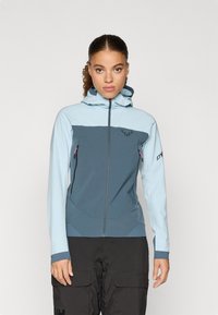 Švarkas su užtrauktuku ir gobtuvu šviesiai mėlynos ir tamsiai žalią spalvų. Jame yra elastinga medžiaga, dvi šoninės kišenės ir logotipo detalė ant krūtinės.