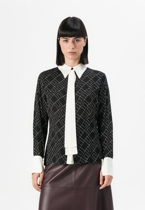 Black patterned blouse with a white collar and tie, featuring a diamond design and solid white cuffs, paired with a burgundy leather skirt.