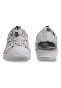 Kevyet, avonaiset kengät valkoisena, joissa on teksturoitu synteettinen päällinen, elastiset nauhat ja vetotapit. Pehmeä pohja mukavuutta varten.