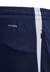 Marineblaue Sportshorts aus strukturiertem Stoff, mit weißem Seitenpanel und einer kleinen Reißverschlusstasche. Mit weißem "BECOOL"-Logo.