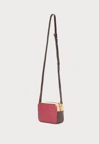 Borsa a tracolla con parte frontale in bordeaux, fondo marrone e parte superiore beige. Presenta una zip dorata e una tracolla sottile e regolabile. Materiale in pelle strutturata.