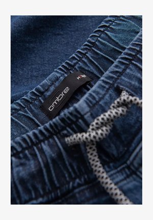 Shorts in denim con elastico in vita, con un'etichetta nera con la scritta "ombre" e una coulisse a motivo check. Colore blu scuro.