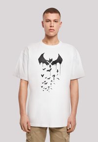 Balta trumpa rankovė t-shirt marškinėliai su juodu šikšnosparniu ir skraidančių šikšnosparnių grafika su lašais. Apvalus kaklas, laisvas kirpimas, minkšta audinio tekstūra.