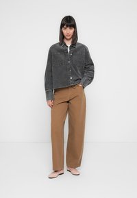 Gray corduroy shirt jacket with two front pockets, paired with high-waisted, wide-leg brown trousers and light pink flats.