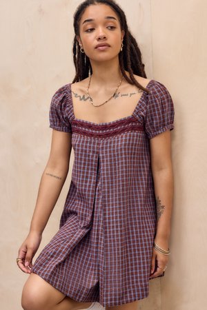 Vestido a cuadros en rojo y azul con mangas abullonadas, escote cuadrado y detalles de encaje. Tela suave con un corte relajado y detalle de pliegue central.