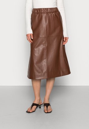 Brun lædernederdel med elastik i taljen, midlængde, glat tekstur, med en lige pasform og enkle syningsdetaljer. Båret med sorte sandaler.